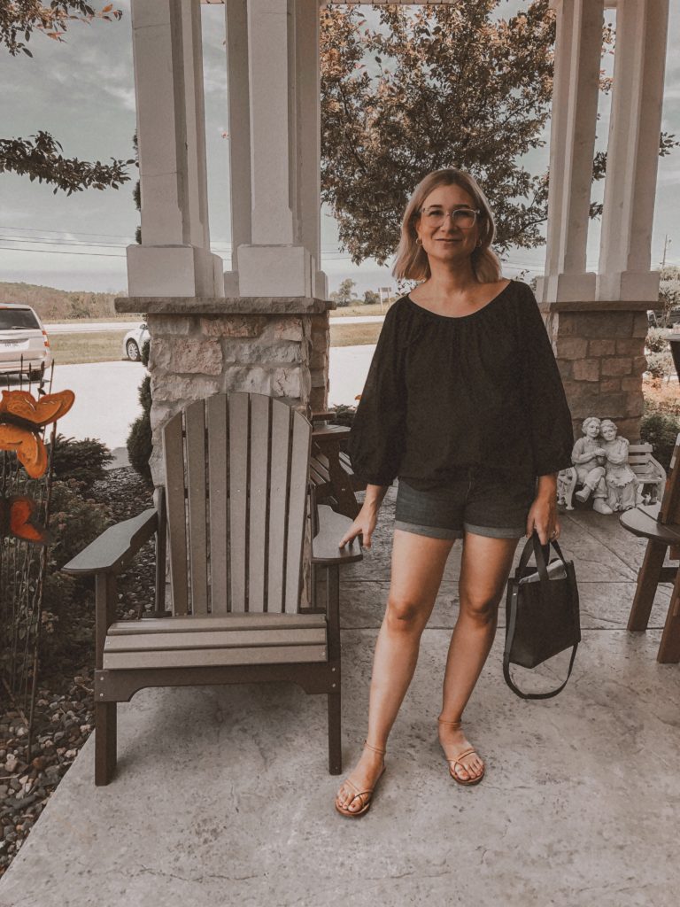 at a market in sturgeon bay wisconsin, everlane air blouse in black, balloon sleeve blouse, black blouse for summer, maternity shorts, nude sandals, nisolo sandals, strappy sandals, gladiator sandals, mini day tote from Everlane, short blonde hair